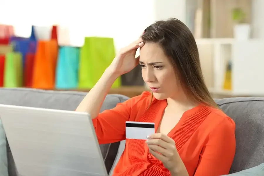 Consumidora diante do computador com cartão de crédito na mão